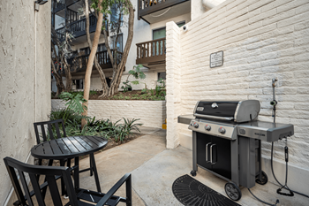 A black grill is on a patio with a table and chairs.